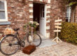 Vélo avec une valise ancienne et un panneau indiquant des directions à l'Hôtel Koru dans le Brabant-Wallon